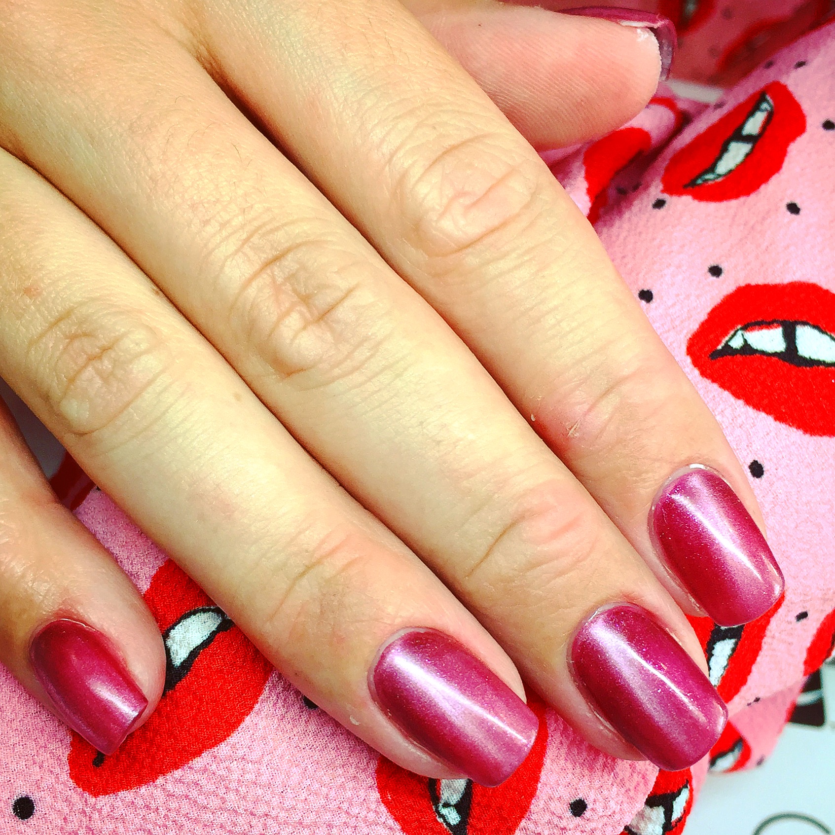 Bordeauxrode nagels met cat-eye glans op een doek met lippenprint
